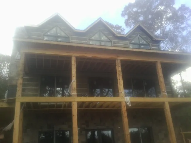 Dormers and porch framing on a large log home under construction — Roof Coating work by our crew in Mason