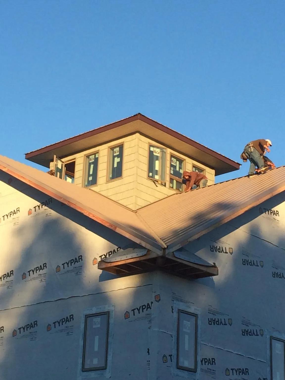 Roofers working around a rooftop cupola on a new metal roof at sunset — Roof Waterproofing in Mason by Roofing Brothers